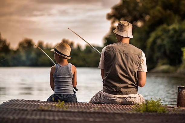 Rear view of a father and son fishing from the pier