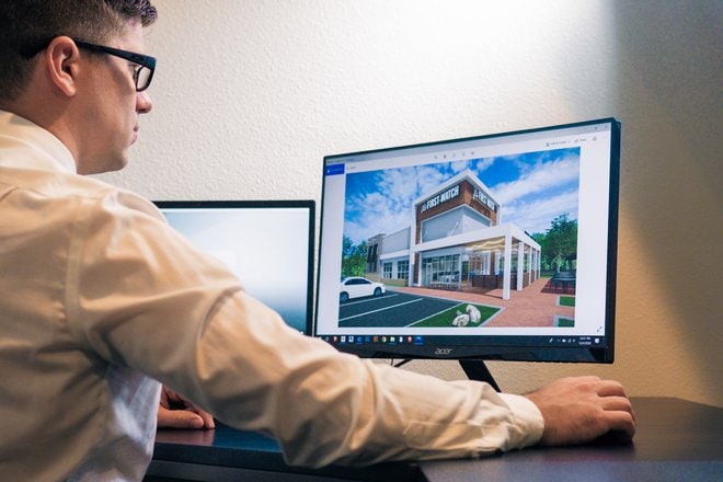 a man sitting at a desk looking at a computer screen